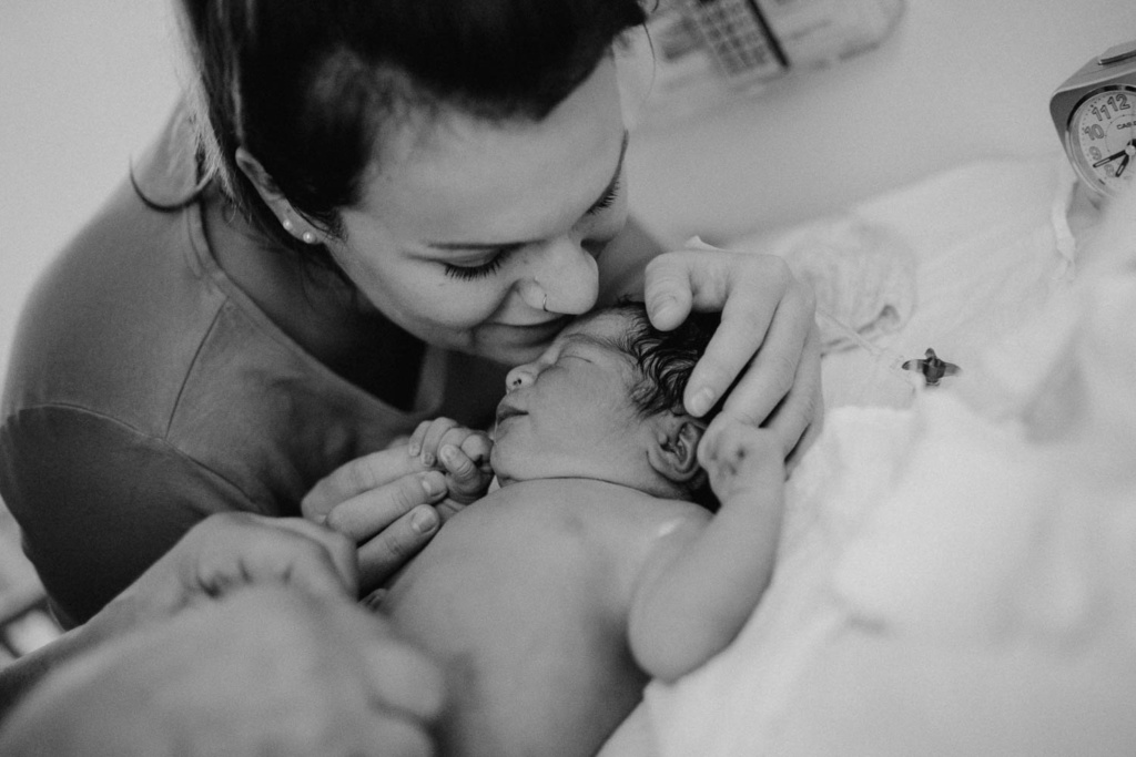 Mutter gibt frischgeborenem Baby erster Kuss
