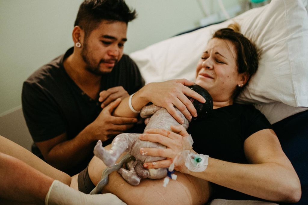 Geburtsfoto von frischgeborenem Baby mit seinen Eltern