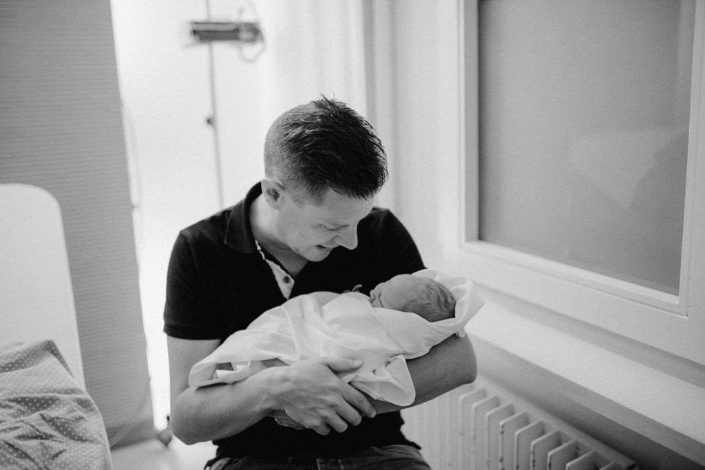 Papa mit frischgeborenem Sohn im Arm