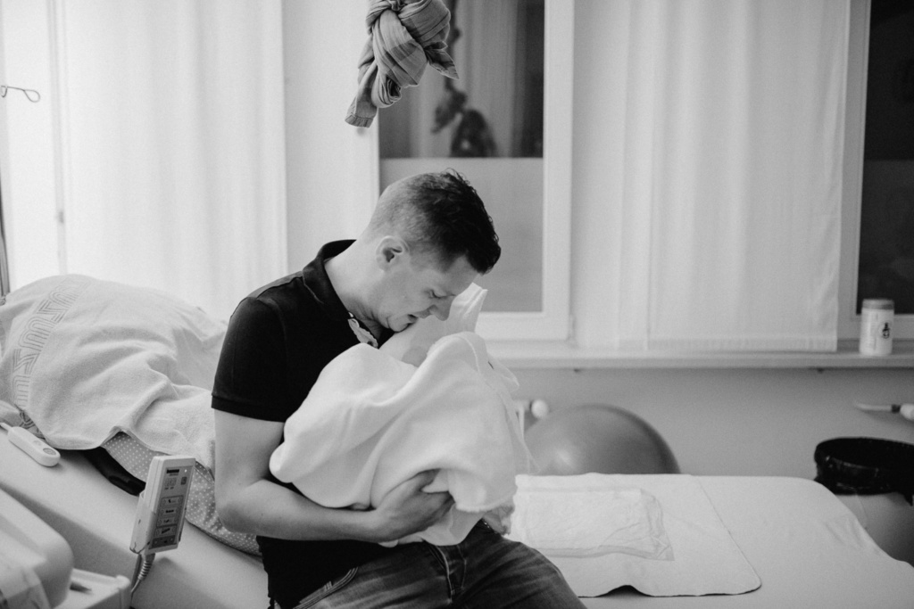 Papa mit frischgeborenem Sohn im Arm