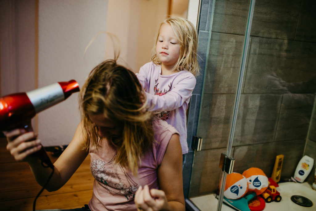 Kind hilft Mama beim Haare föhnen