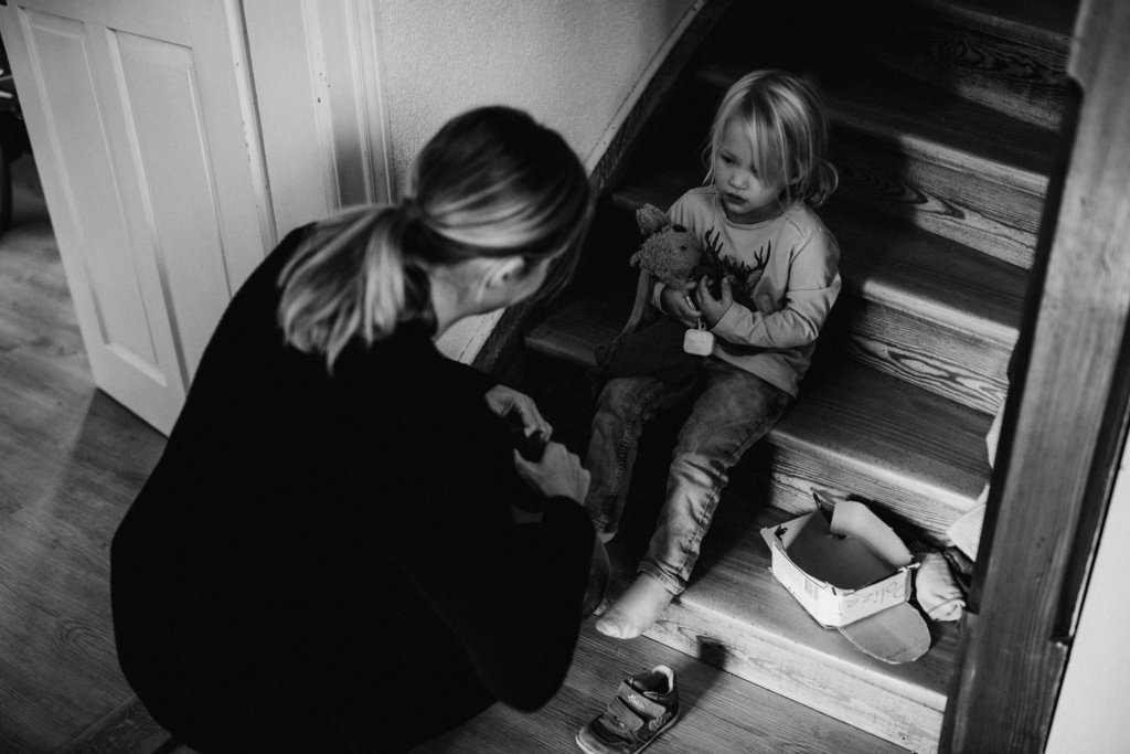 Mama zieht Kind die Schuhe an