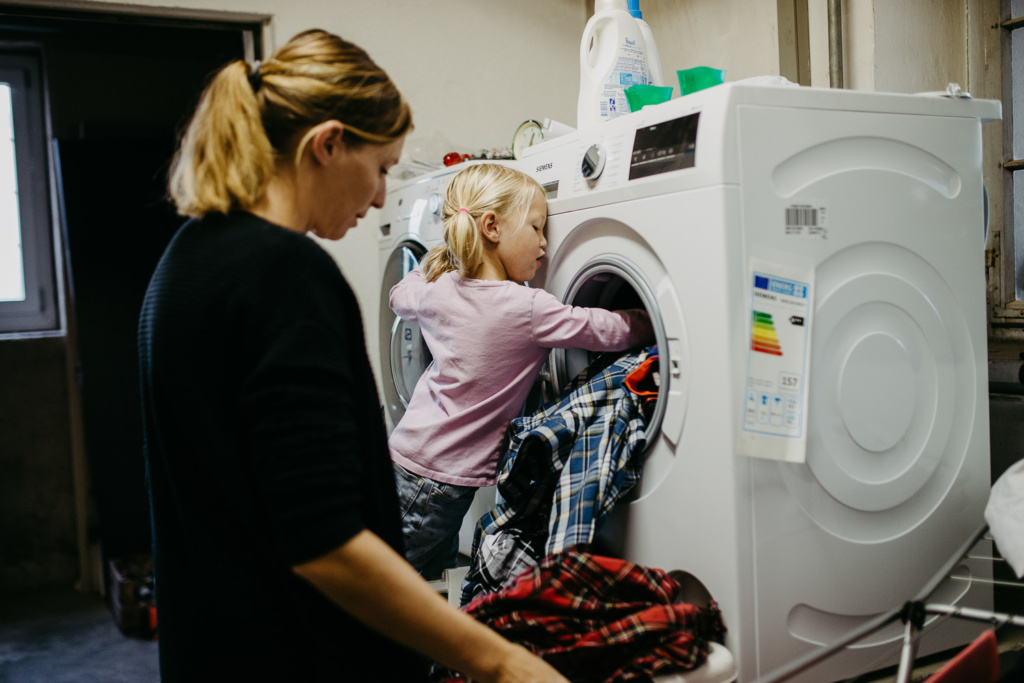 Kind hilft Mama beim Wäsche waschen