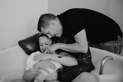 frischgebackene Eltern halten ihr Baby im Arm nach der Geburt