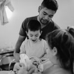 Geburtsfotograrfie einer kleiner Familie, die ihr neues Familienmitglied bestaunt